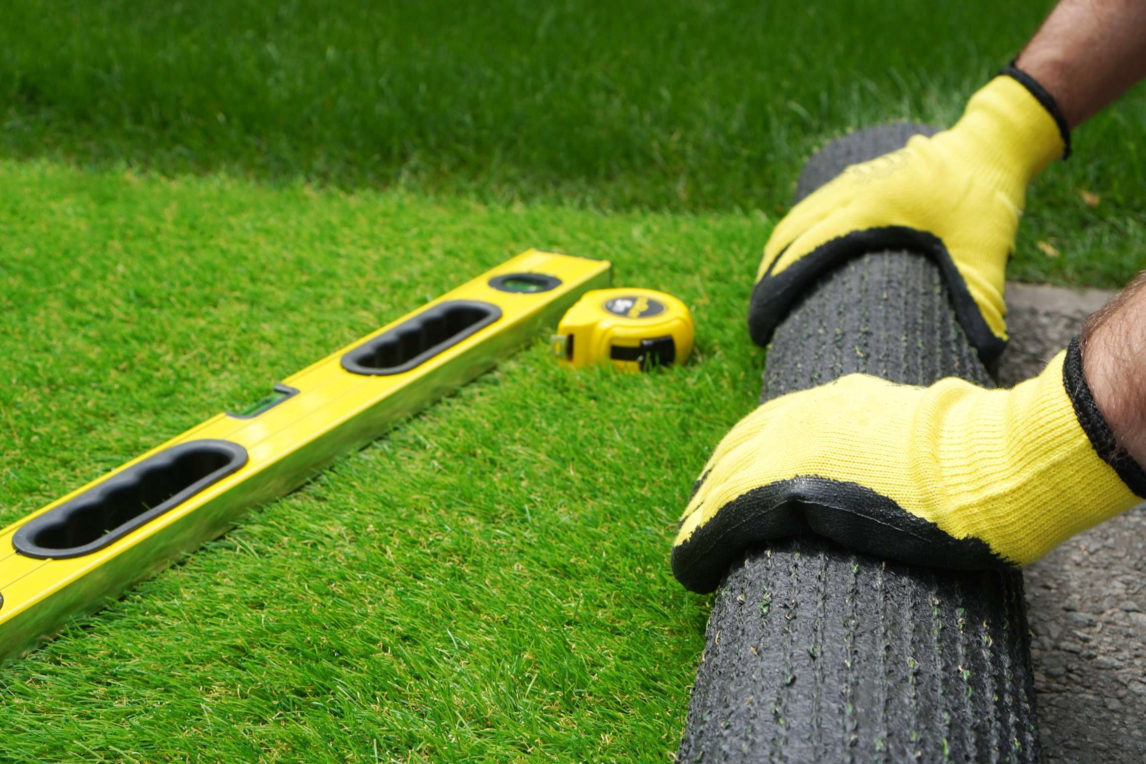 landscaper tools laying out artificial turf