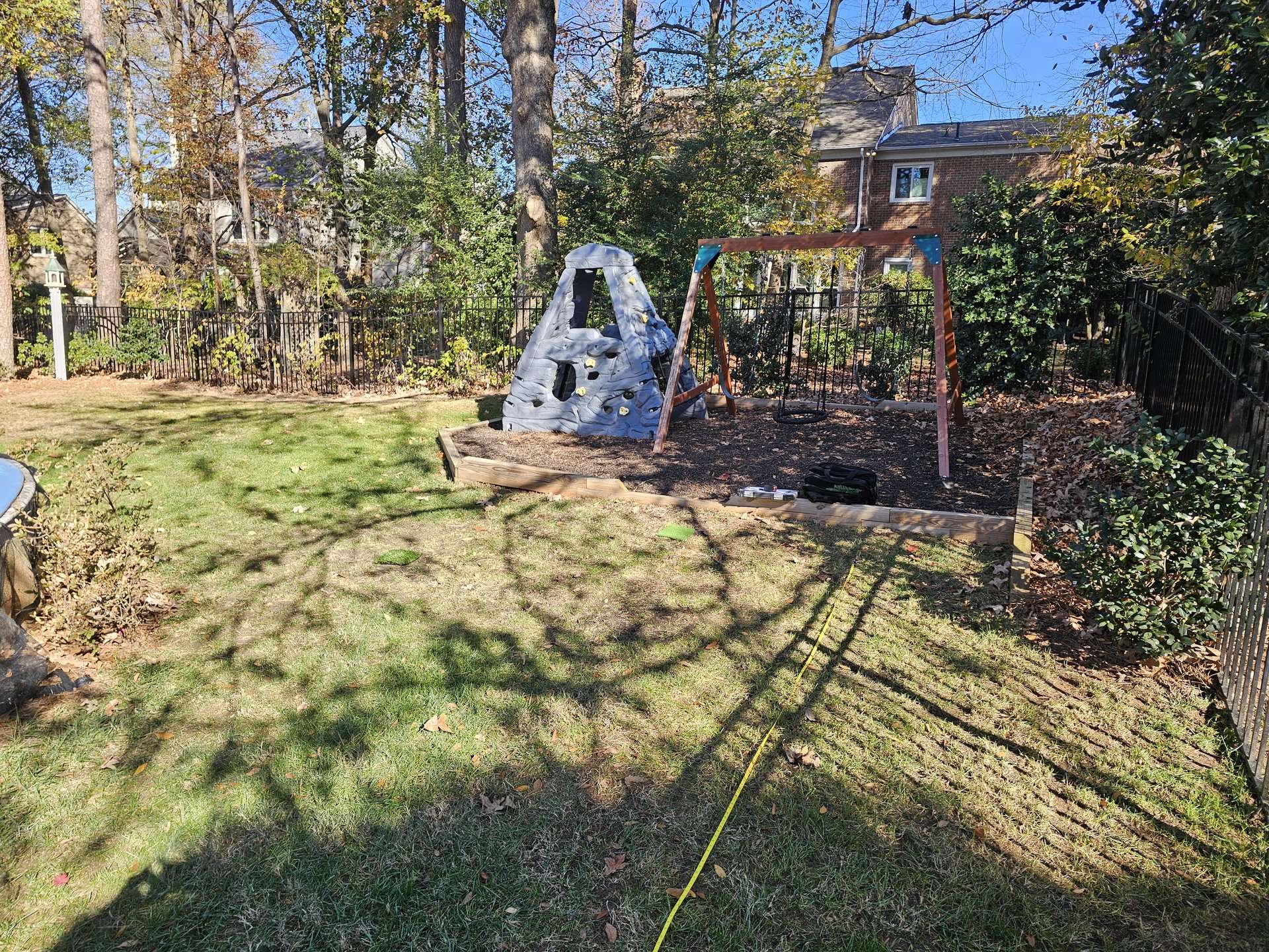 child swing set playground in corner of backyard